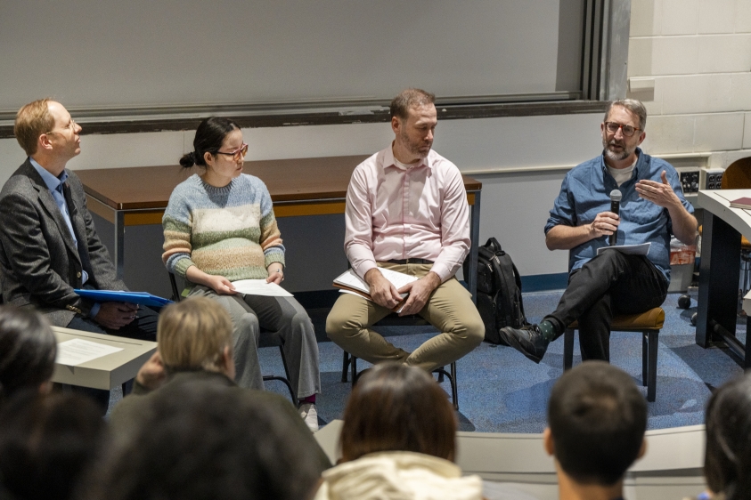 Four faculty, seated, discuss assessment in a lecture hall