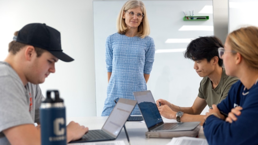 Faculty member observes students working on laptops
