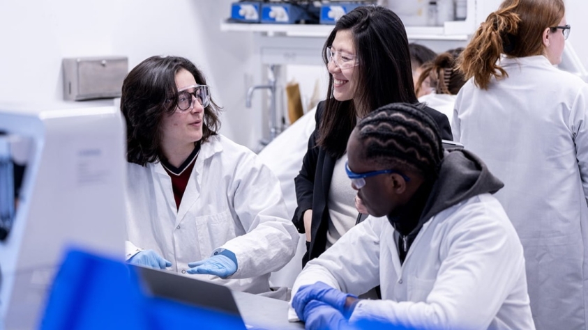 Faculty member interacts with students in a lab