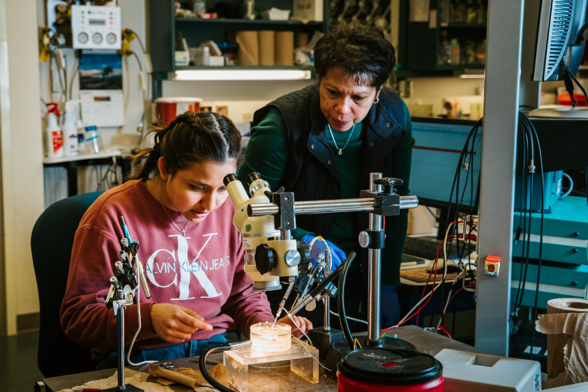 A female professor guides a female student through a lab experiment