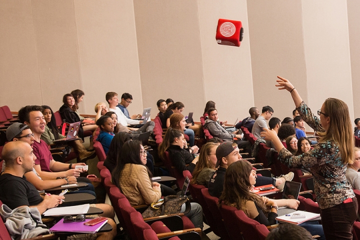 Instructor throws a “catch box” microphone to a student in a large lecture class that is part of the Active Learning Initiative
