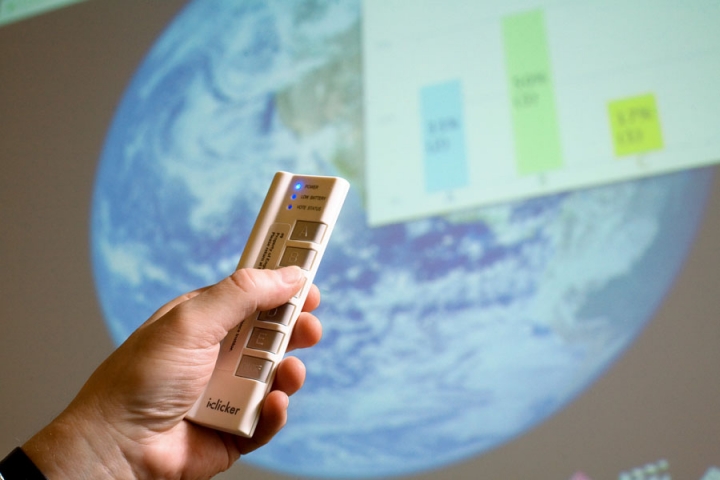 Hand holding an iClicker remote in front of a projected screen