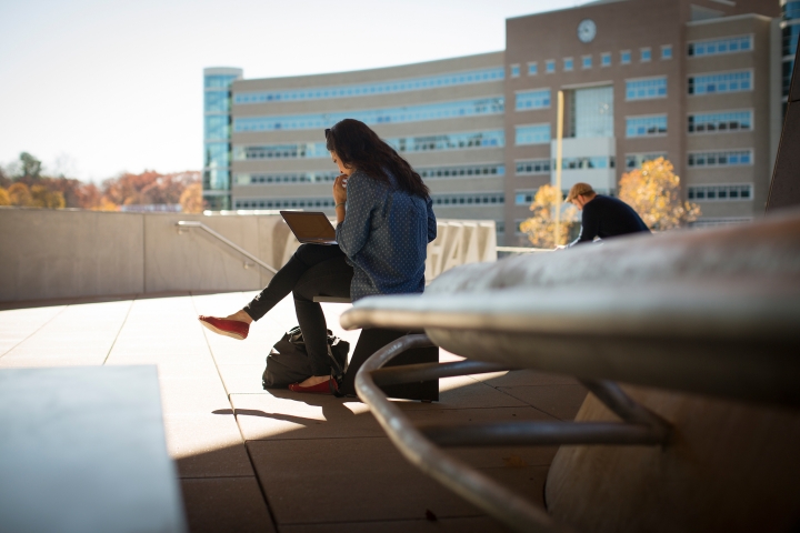 People working on computers with Rhodes Hall in the background