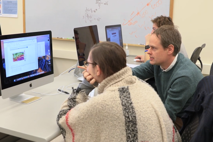 Assistant professor Peter Hitchcock working with students on computer