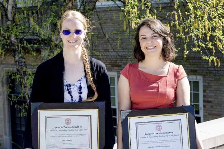 Two young women hold certificates of award