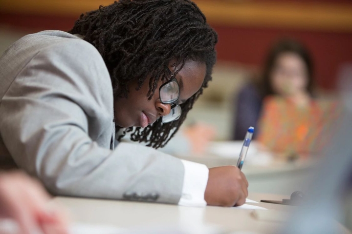 student leans over paper during events