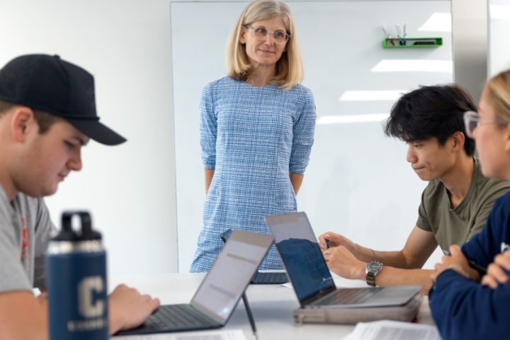 Faculty member observes students working on laptops