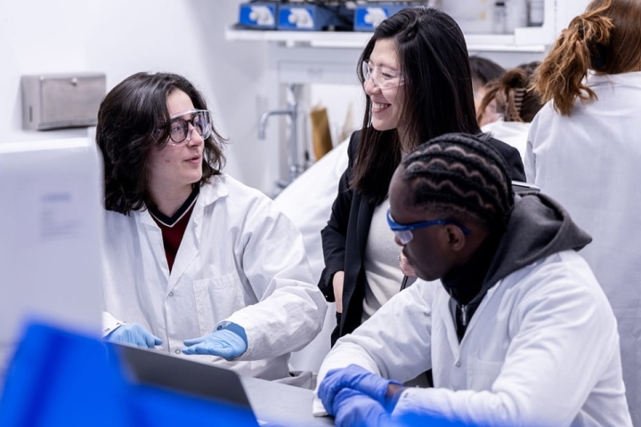 Faculty member interacts with students in a lab