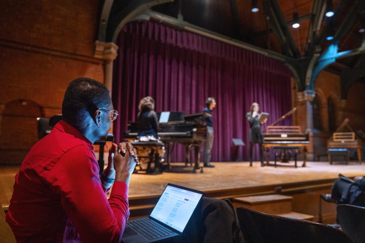 A man watches a vocal class rehearsal